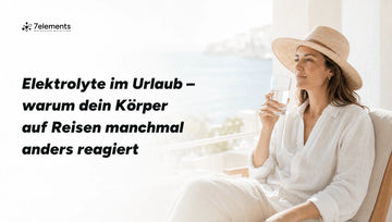 Frau mit Sonnenhut am Strand mit einem Glas Wasser – Elektrolyte im Urlaub